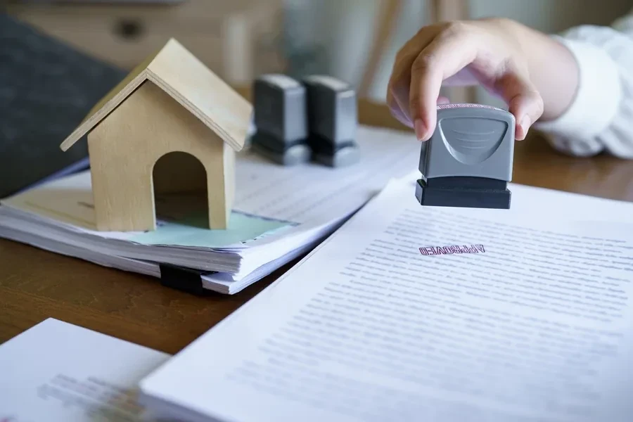 Approval stamp on mortgage papers next to a house model, representing Fannie Mae value acceptance
