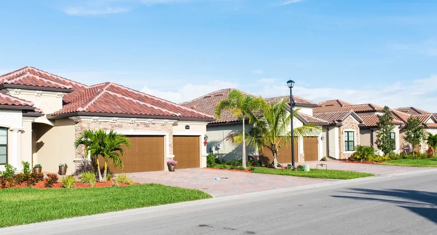 Row of Mediterranean-style Florida townhomes with tile roofs and palm trees in an HOA community