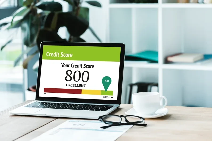 Laptop on a wooden desk showing a credit score dashboard next to paperwork, the kind of check a Florida buyer runs before applying for a mortgage