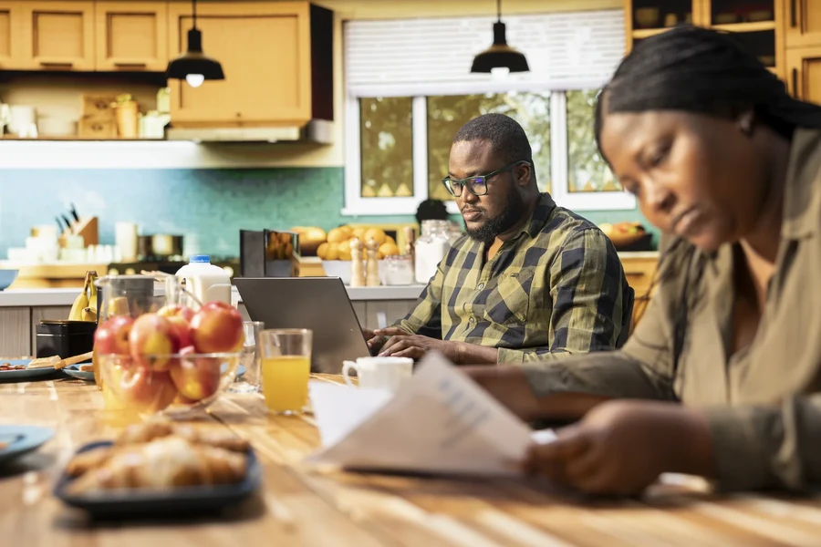 Family sitting at a kitchen table going through bills and paperwork together before applying for a Florida mortgage