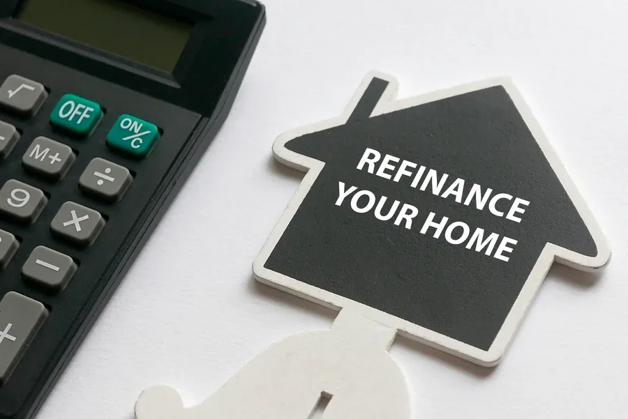 Refinance written on a chalkboard beside a calculator and a small model house