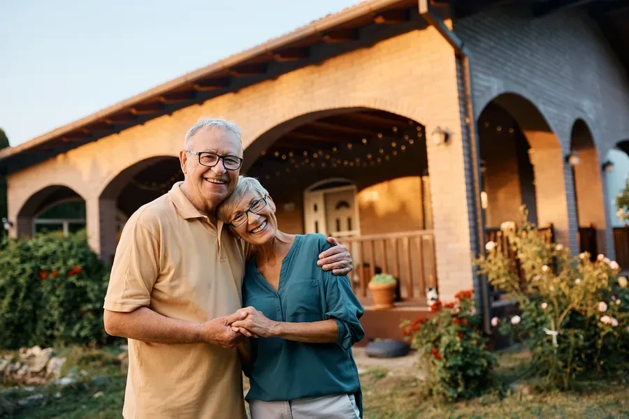 Happy senior couple relaxing outside their Florida home in the evening, the kind of seasonal buyers weighing renting against owning