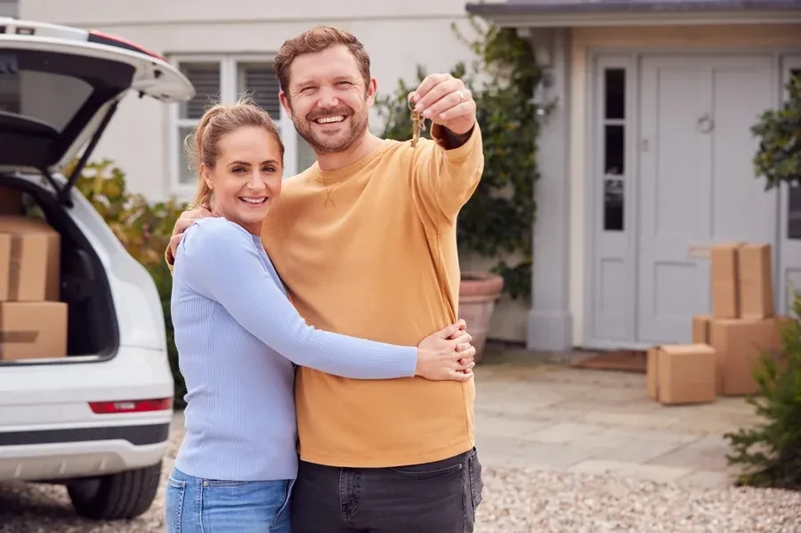 Smiling couple holding the keys to their new Florida home in front of the porch, the kind of buyers who finance with a USDA or FHA loan